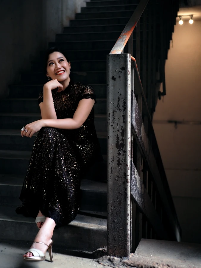 Ang Mei Foong in a black lace gown on a staircase